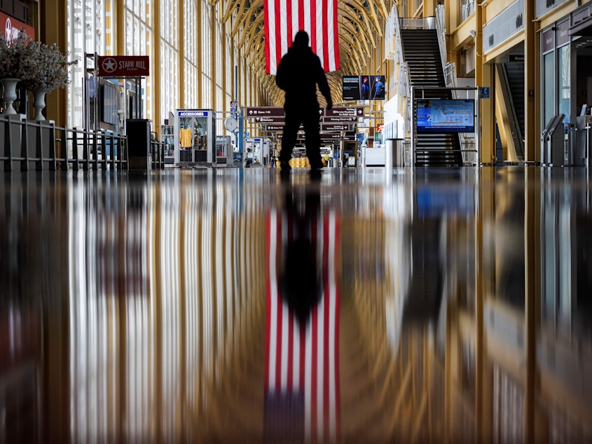 caption: An airport employee walks through Reagan National Airport in Arlington, Va., earlier this year. On Thursday, the Centers for Disease Control and Prevention warned that Americans should refrain from traveling for the upcoming holiday.