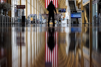 caption: An airport employee walks through Reagan National Airport in Arlington, Va., earlier this year. On Thursday, the Centers for Disease Control and Prevention warned that Americans should refrain from traveling for the upcoming holiday.