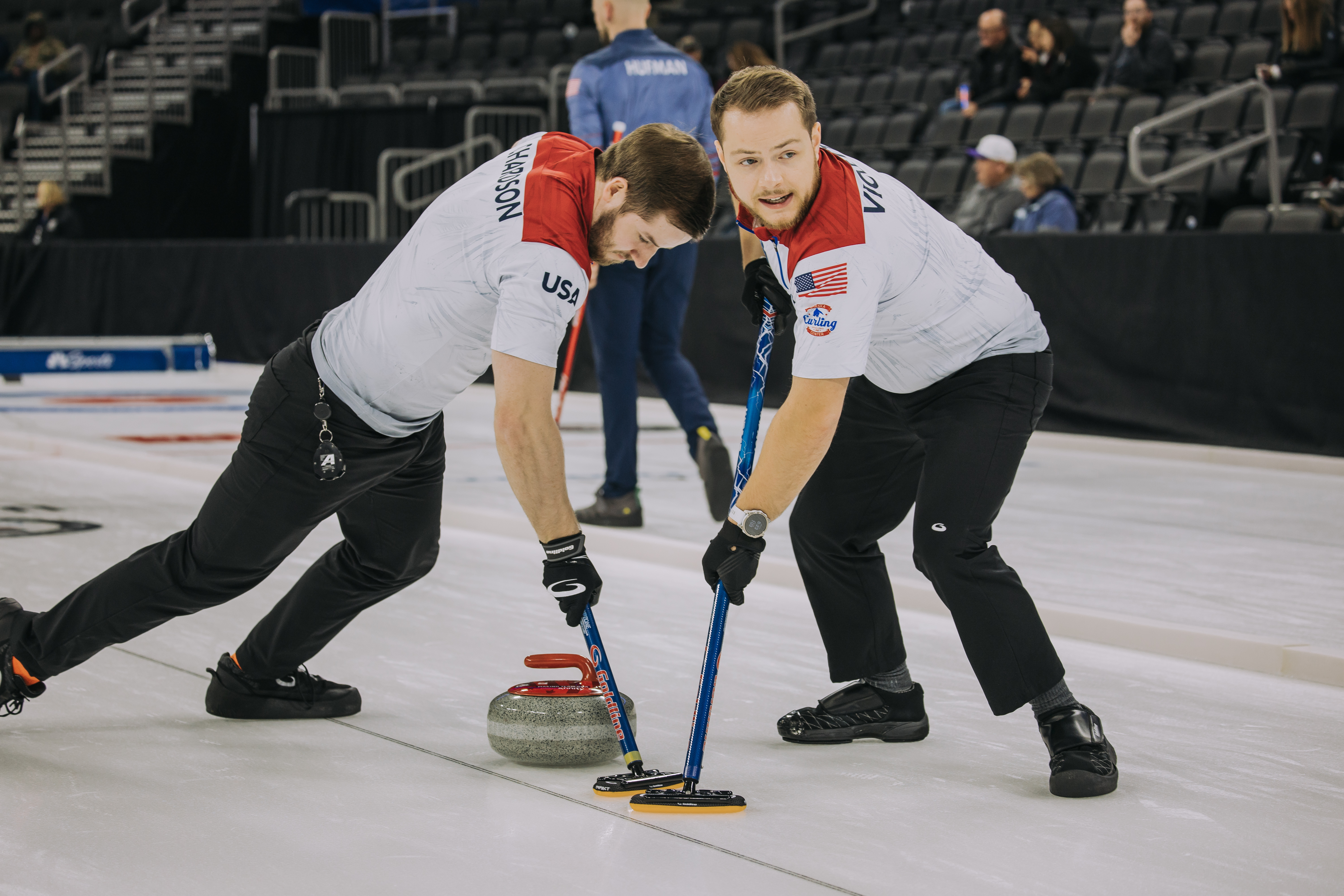 caption: Luc Violette, on the right, and Ben Richardson, sweep in front of a throw during a curling competition with Team USA. The two Seattle curlers will be part of a team representing the U.S. at the upcoming Olympics in Italy.