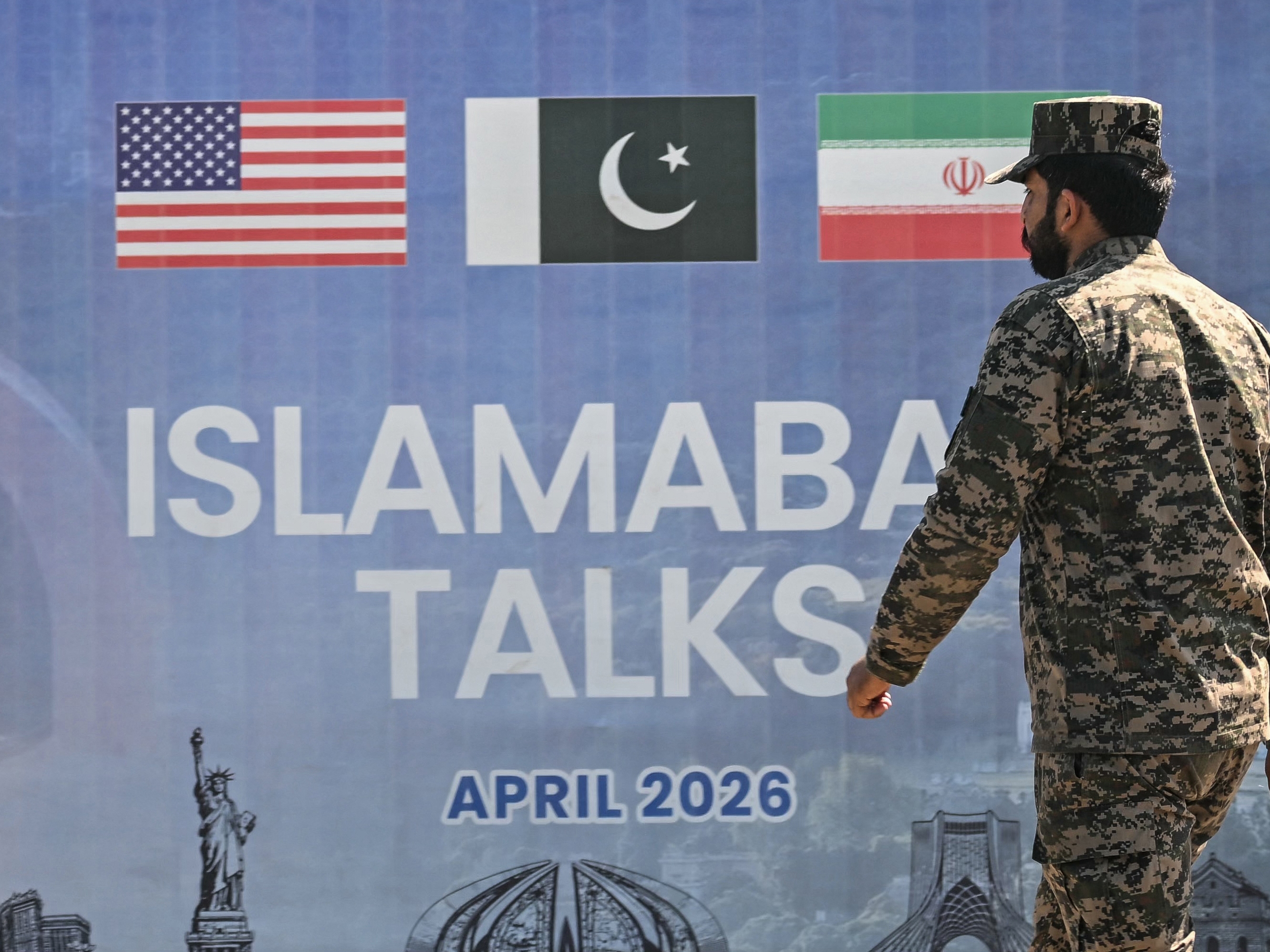 caption: A Pakistani Ranger walks past a billboard for the U.S.-Iran peace talks in Islamabad on April 12, 2026. The talks, led by Vice President JD Vance, produced no concrete movement toward a peace deal.
