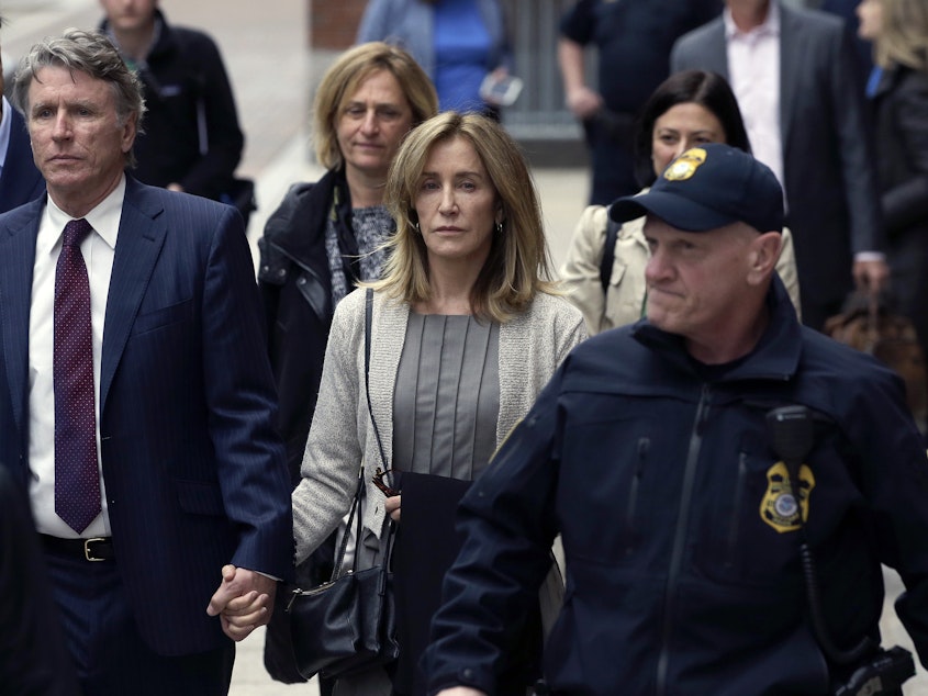 caption: Felicity Huffman, center, departs federal court with her brother Moore Huffman Jr., left, Monday, May 13, 2019, in Boston, where she pleaded guilty to charges in a nationwide college admissions bribery scandal.