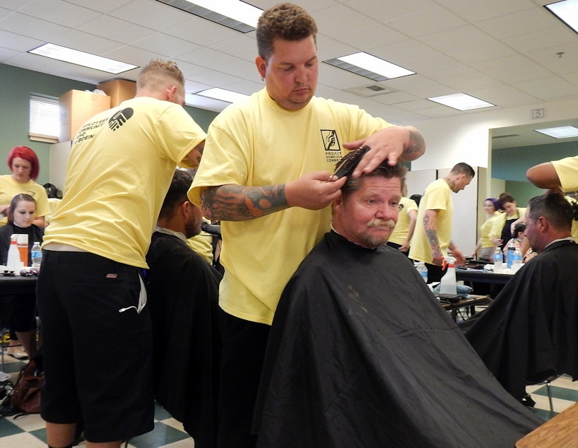 caption: Homeless Army veteran Marvin Stanfield gets a free haircut from Adam Nolin of the Paroba College of Cosmetology.