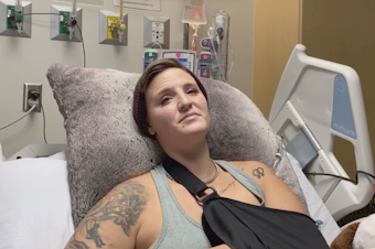 caption: Protester Diaz Love, 32, sits in their hospital bed at Harborview Medical Center on Wednesday, July 22 recovering from multiple injuries. Diaz and another protester, Summer Taylor, were struck by driver Dawit Kelete in the early morning hours of July 4 amid a demonstration against racism and police brutality on Interstate 5. 