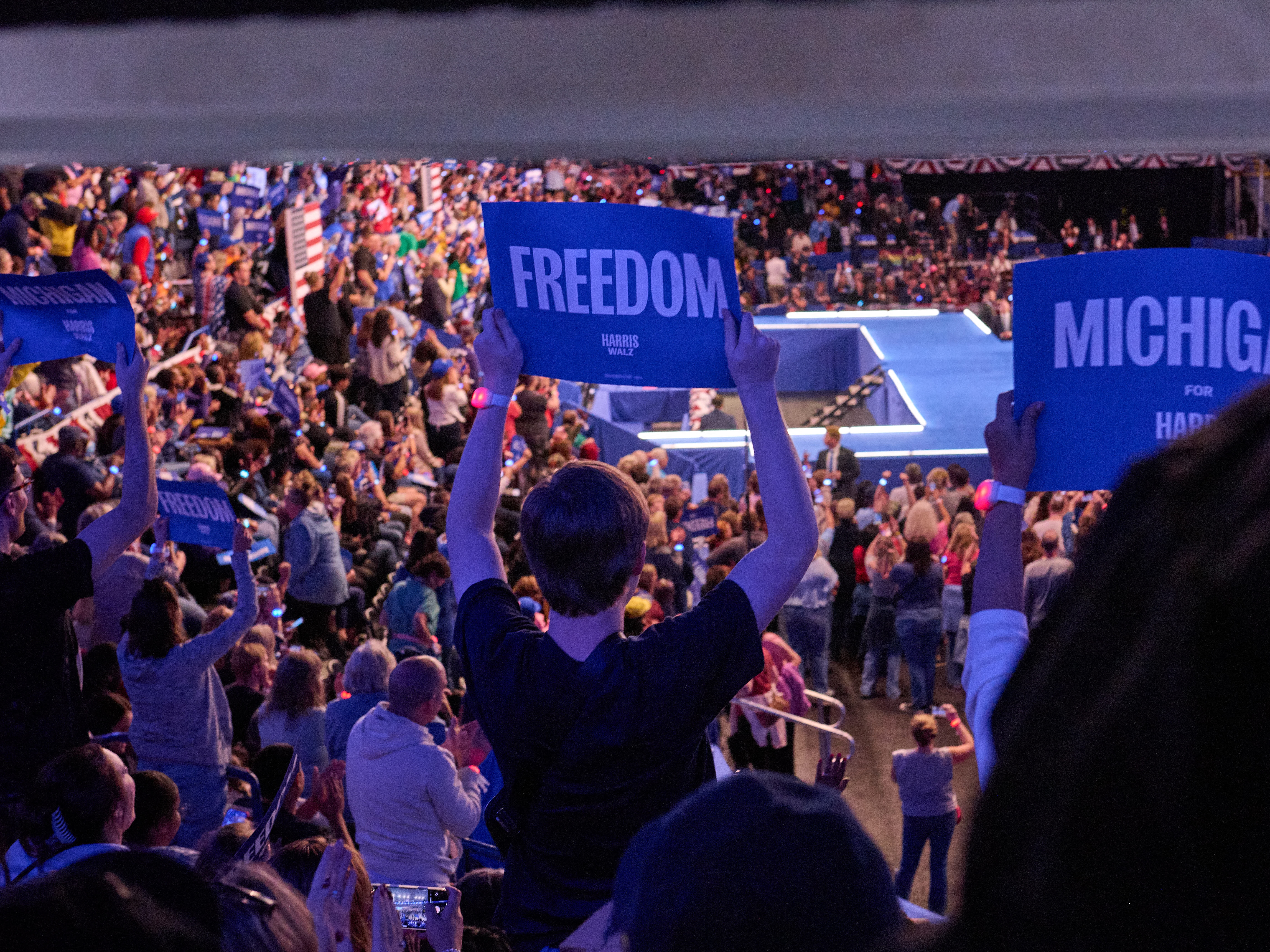 caption: Supporters watch Vice President Harris speak during a rally in Flint, Mich.