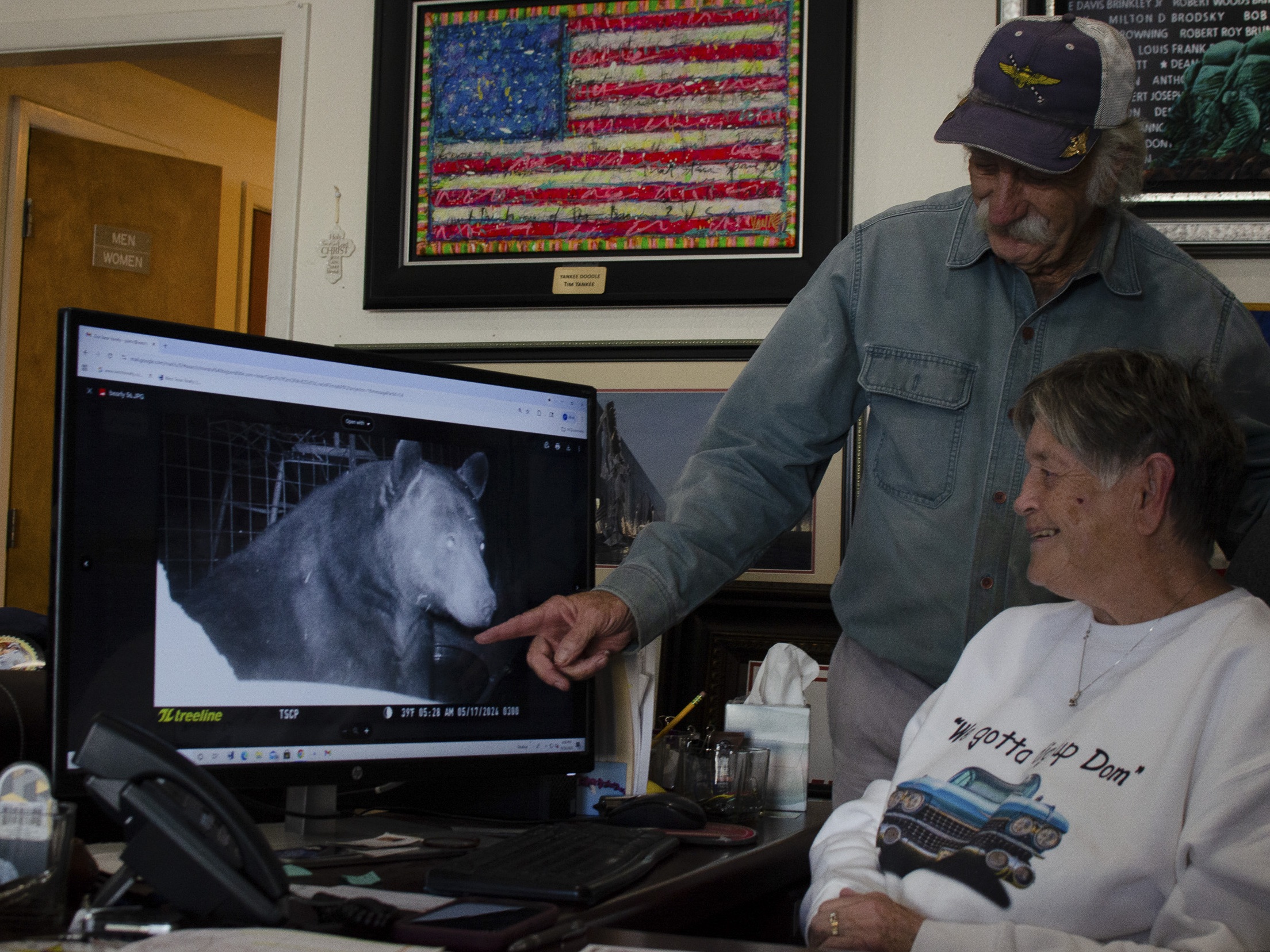 caption: Ken Clouse and his wife Pam look at a still image taken from a game camera on their porch. The couple says in the last two years, they've regularly seen black bears in their neighborhood south of Alpine, Texas.