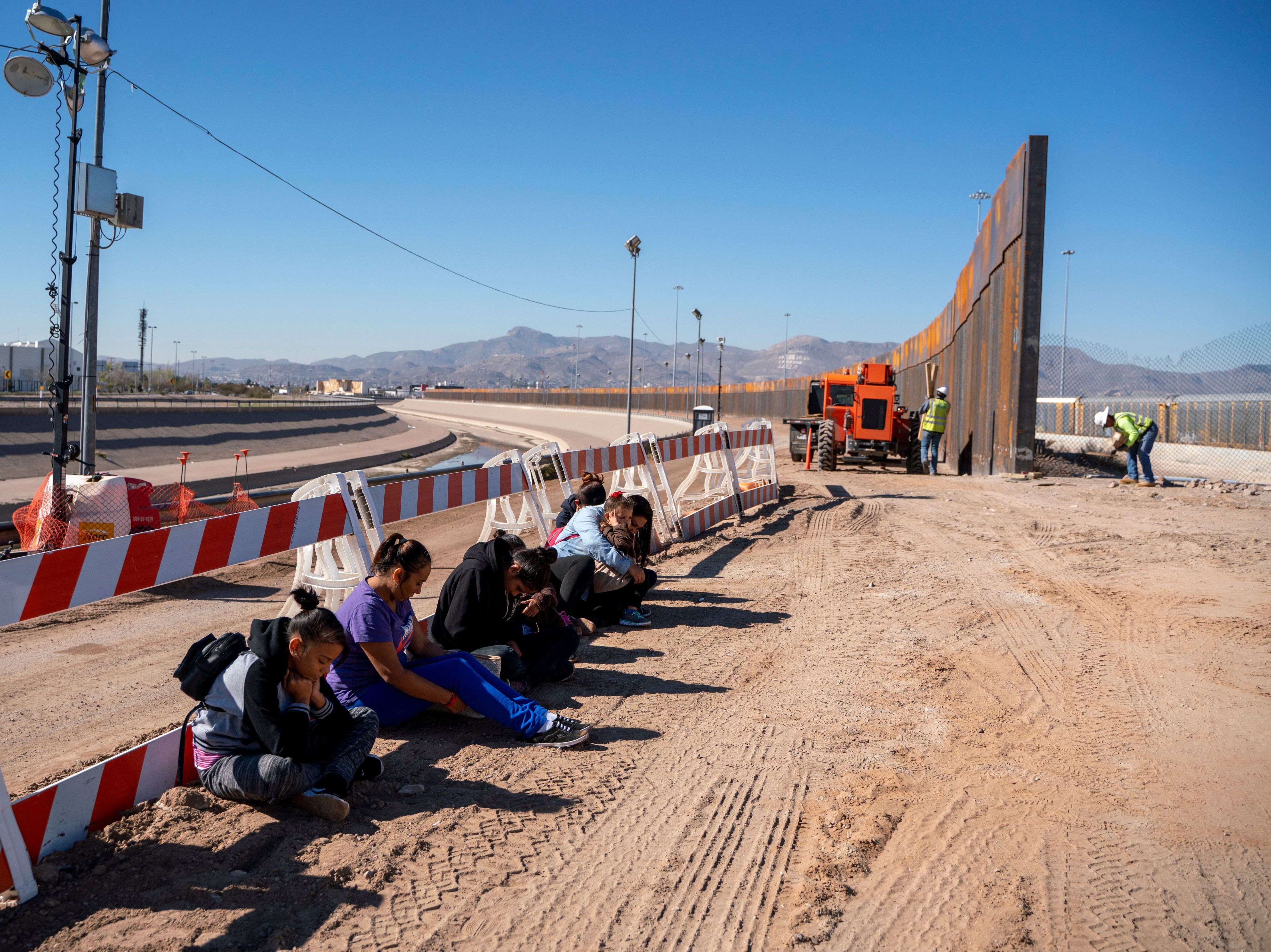 caption: Salvadoran migrants wait for transportation after turning themselves in to U.S. Border Patrol agents in El Paso, Texas — where a border fence is under construction. The Pentagon says it will spend up to $1 billion to help build the fence.
