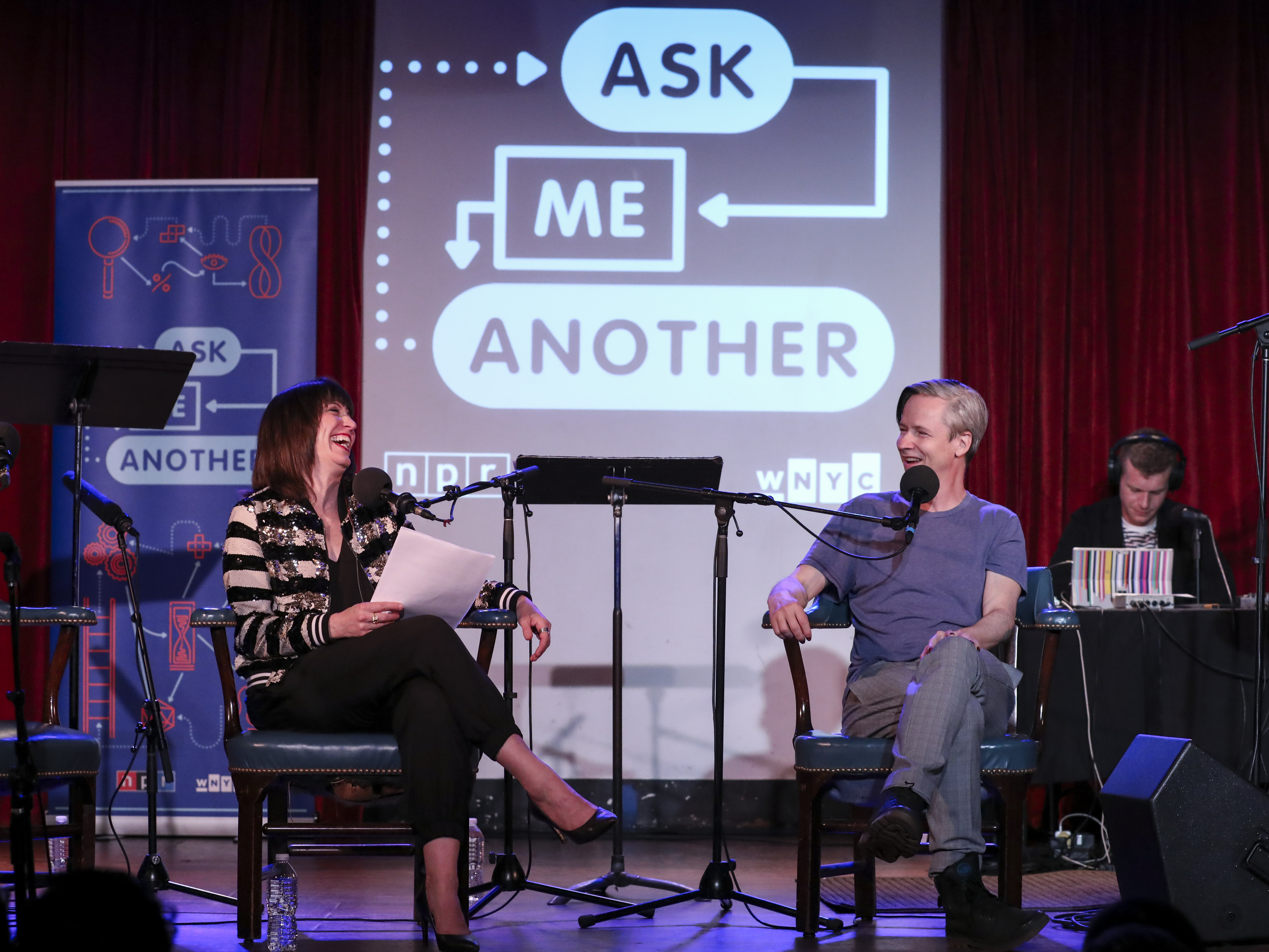 caption: <em>Ask Me Another </em>host Ophira Eisenberg interviews John Cameron Mitchell at the Bell House in Brooklyn, New York.