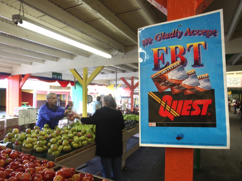caption: A sign announces the acceptance of electronic benefit transfer cards at a farmers market in California. Anti-poverty groups fear that many low-income people might be pushed off programs such as food stamps under a possible change to how the government measures poverty.