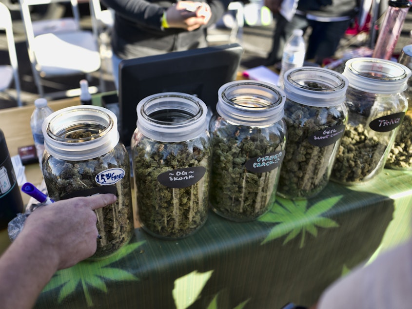 caption: A vendor points to a selection of cannabis strains for sale during a 2018 marijuana festival in California.