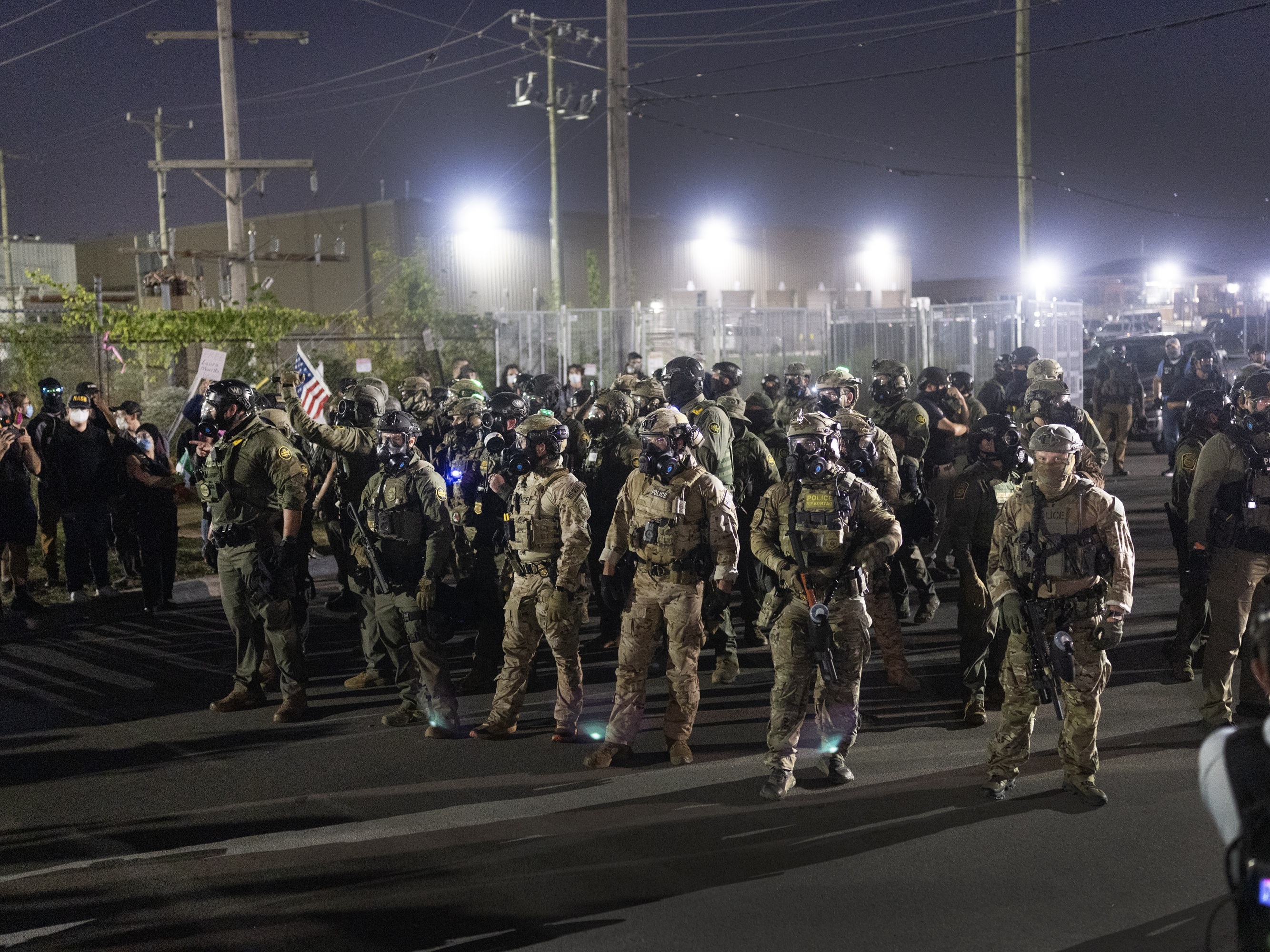 caption: Federal law enforcement agents confront demonstrators protesting outside an immigrant processing center on Saturday in Broadview, Ill.