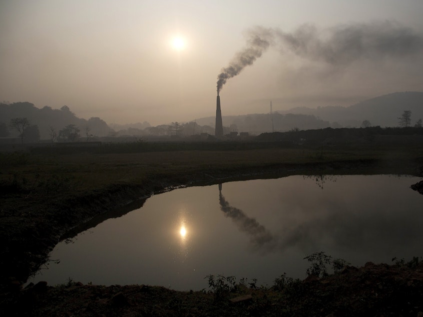 caption: Smoke rises from a brick kiln on the outskirts of Gauhati, India, in 2015. India's pledge this week to reach net zero carbon emissions by 2070 factors into a new, more optimistic, analysis by the International Energy Agency on climate change goals.