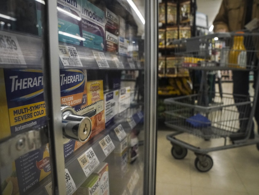 caption: Medications are locked in a glass cabinet at a supermarket.