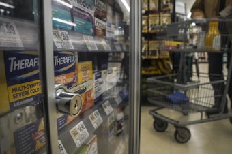 caption: Medications are locked in a glass cabinet at a supermarket.