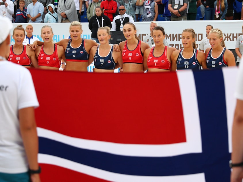 caption: The Norwegian women's beach handball team is being fined for wearing shorts during a recent tournament game. The team is seen here after a game in 2018.