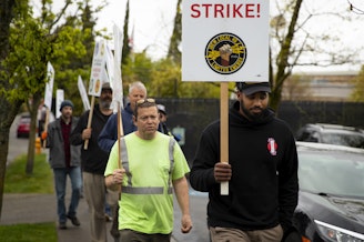 caption: Isaiah Banks, right, leads IBEW Local 46 workers during a picket while on strike on Friday, April 26, 2024, along Stone Avenue North in Seattle. 