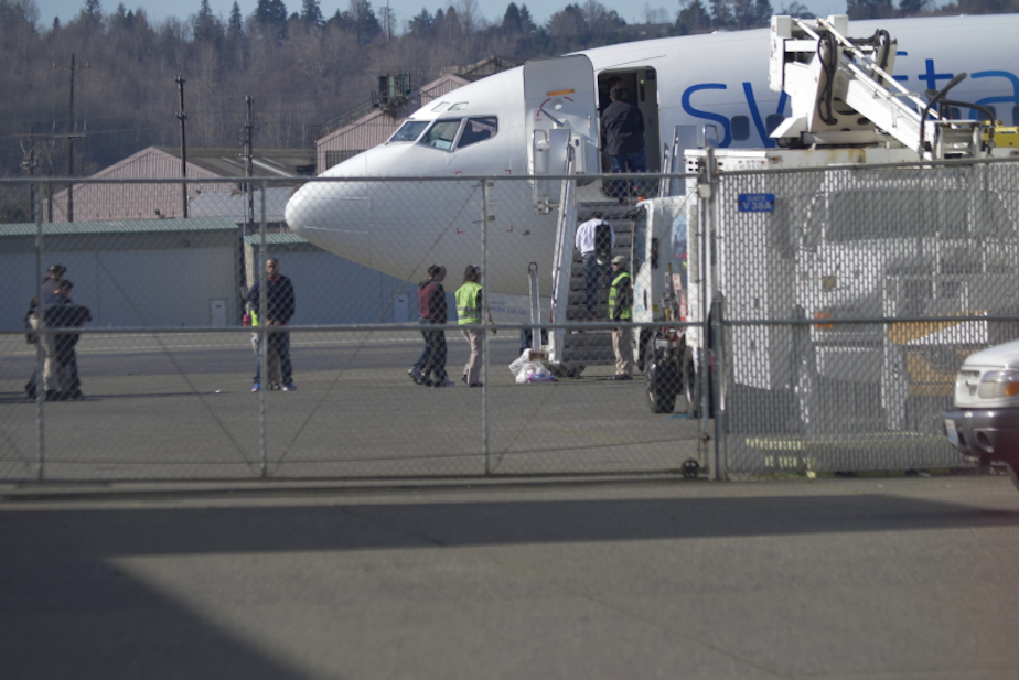 caption: In this still image from a vide, detainees are loaded onto a Swift Air charter flight at King County International Airport (Boeing Field) in Seattle, WA for a February 26 ICE Air flight under callsign RPN 529. 