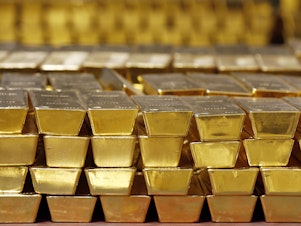 caption: Gold bars are stacked in a vault at the United States Mint, in West Point, N.Y., in 2014. The settlement price for gold futures reached a record high of $1,931 per ounce Monday — and many analysts predict the price will head even higher.