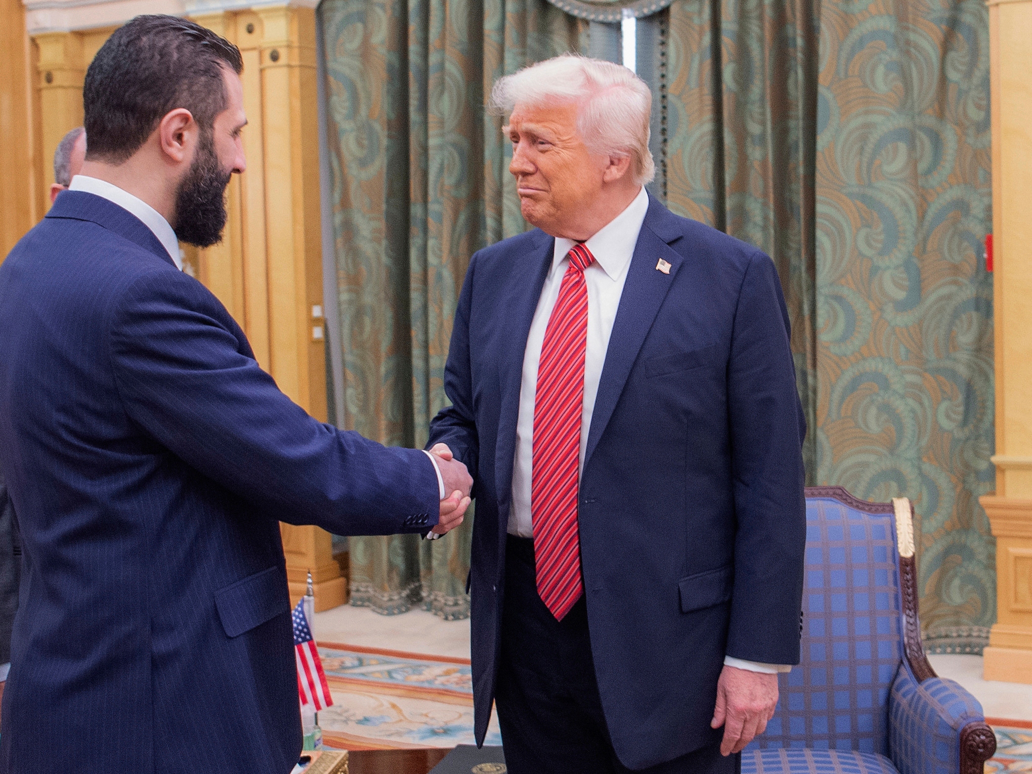 caption: In this photo released by the Saudi Royal Palace, President Trump shakes hands with Syria's interim President Ahmad al-Sharaa, in Riyadh, Saudi Arabia, May 14.