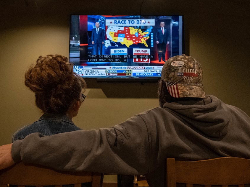 caption: A couple watches the election results at a Republican watch party at Huron Valley Guns in New Hudson, Mich. People watching the results come in saw President Trump outperforming his position in preelection polls.