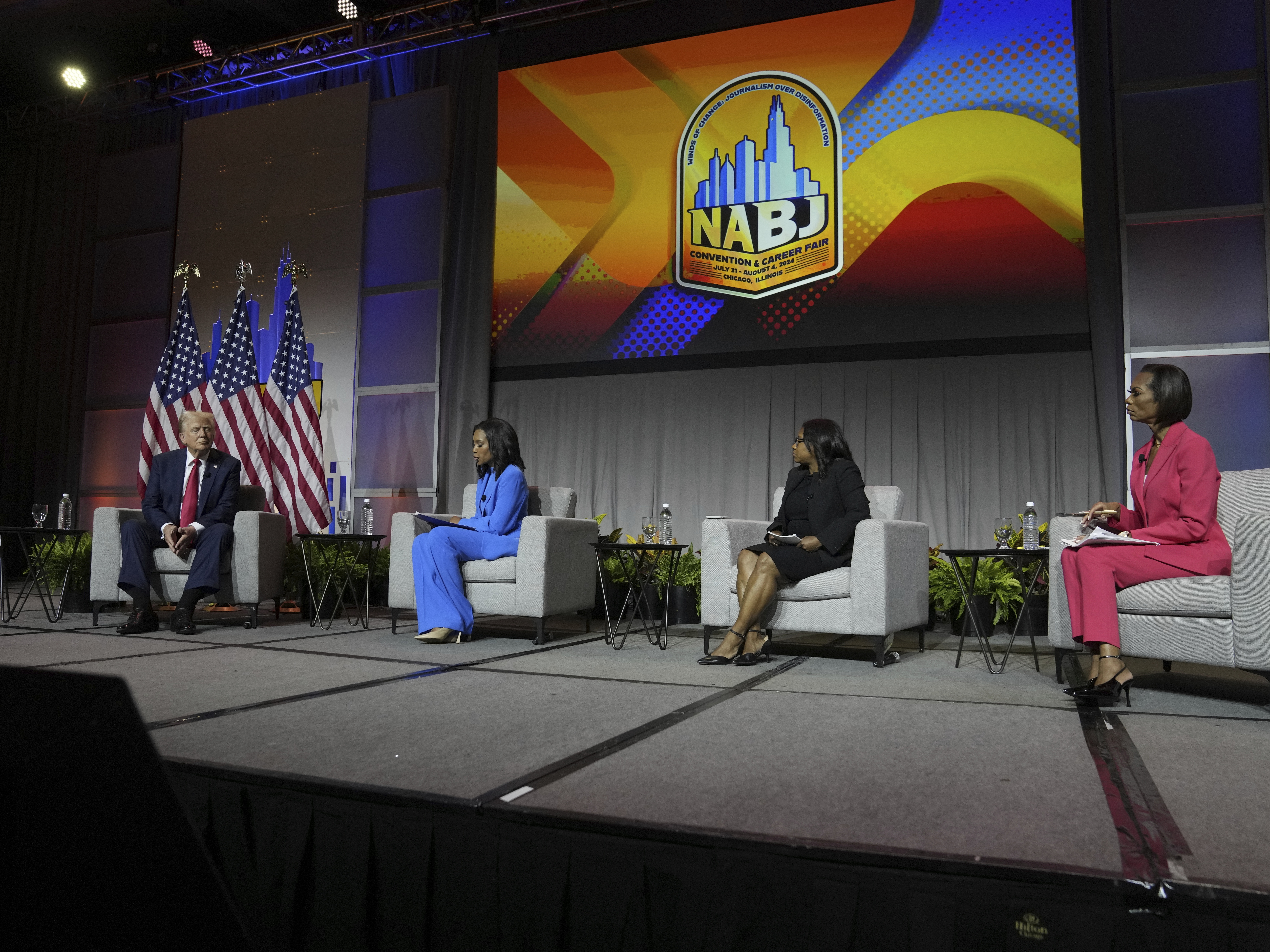 caption: Republican presidential nominee and President Donald Trump speaks at a panel moderated by, from left, ABC's Rachel Scott, Semafor's Kadia Goba and Fox News' Harris Faulkner at the National Association of Black Journalists convention Wednesday in Chicago.