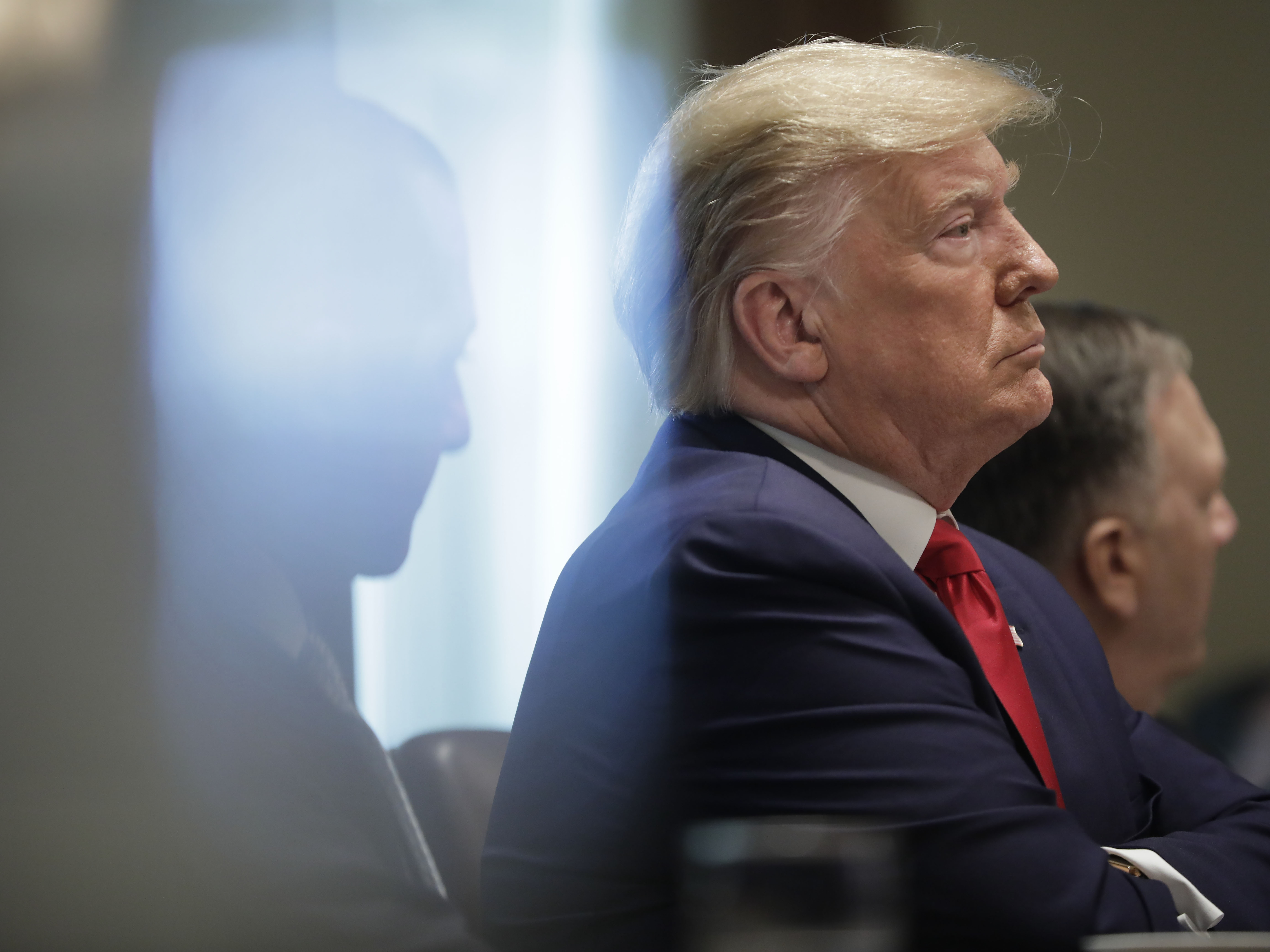 caption: President Trump, arms crossed, listens during a Cabinet meeting in the White House Monday.