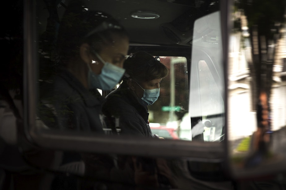 caption: Puget Sound Regional Firefighters Jessi Nemens, left, and Nikki Smith, right, prepare to drive to the residence of a homebound individual to administer a Moderna Covid-19 vaccine, on Monday, May 24, 2021, in Kent.