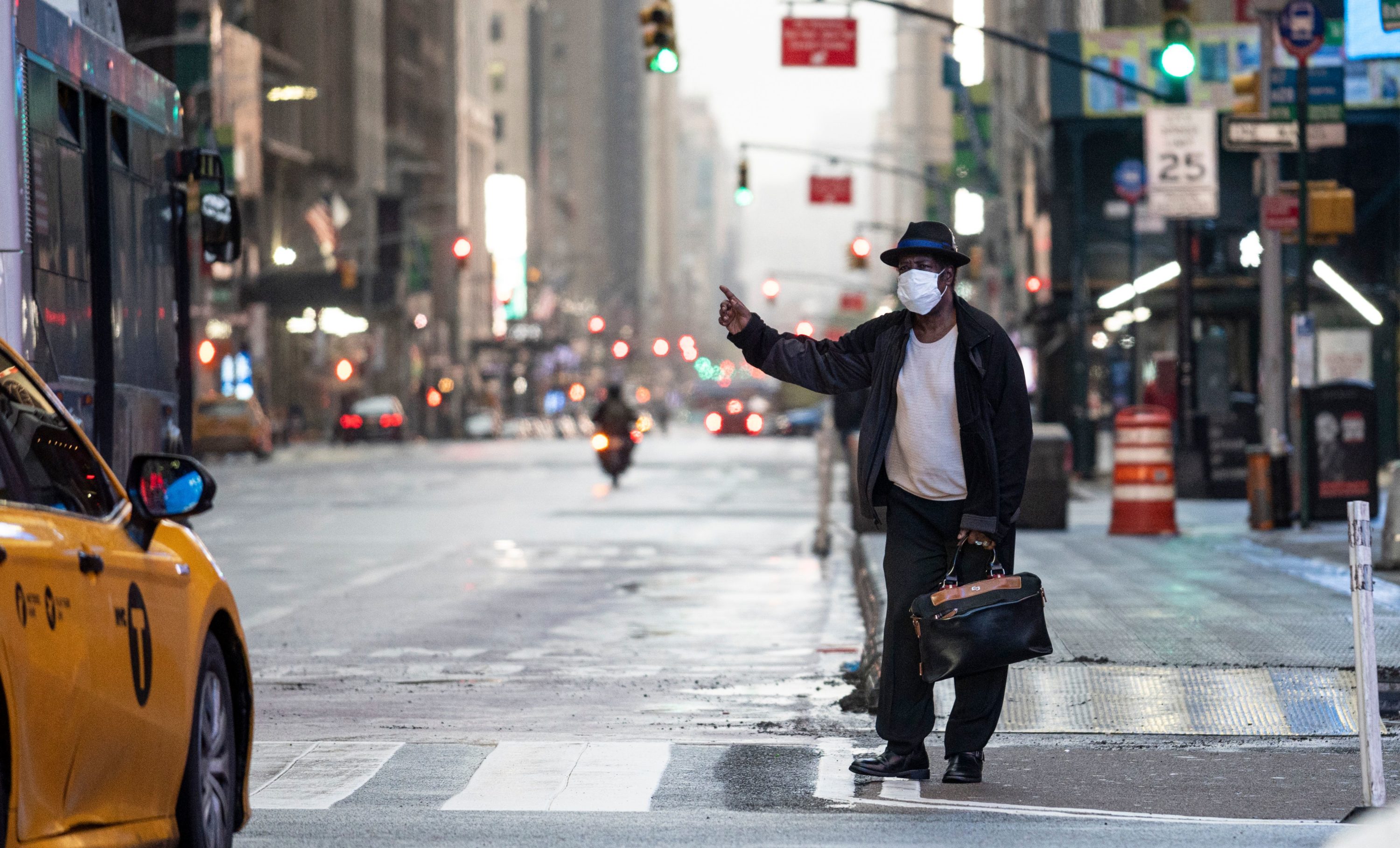 caption: A man wearing a mask tries to catch a taxi at Times Square amid the Covid-19 pandemic on April 30, 2020 in New York City. (JOHANNES EISELE/AFP via Getty Images)