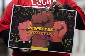 caption: A person holds a sign at a rally to raise the federal minimum wage, on Capitol Hill in Washington, D.C., on May 4.