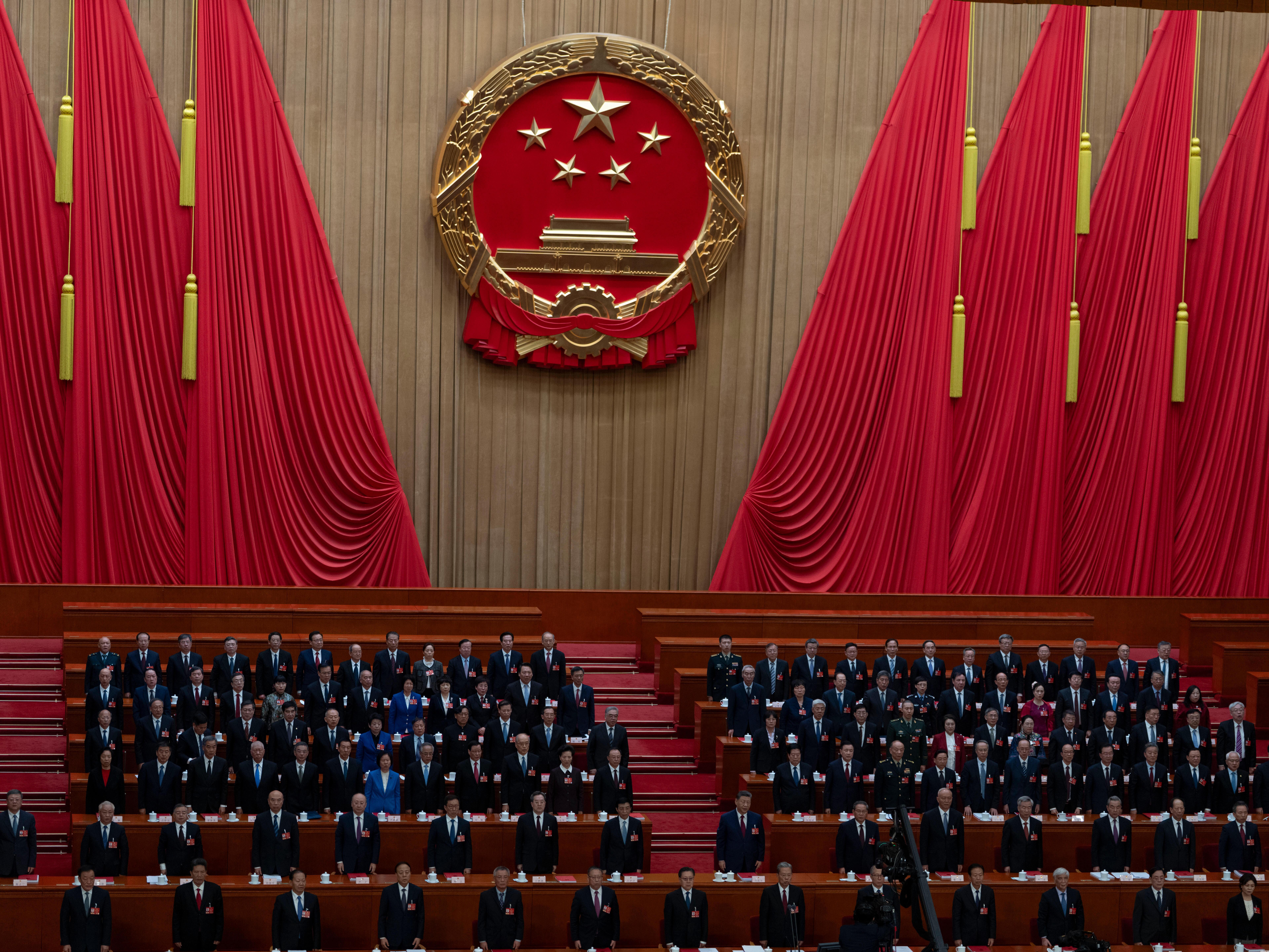caption: Delegates including Chinese President Xi Jinping (center) stand as the national anthem is sung during the closing session of the National People's Congress at the Great Hall of the People in Beijing, Thursday.