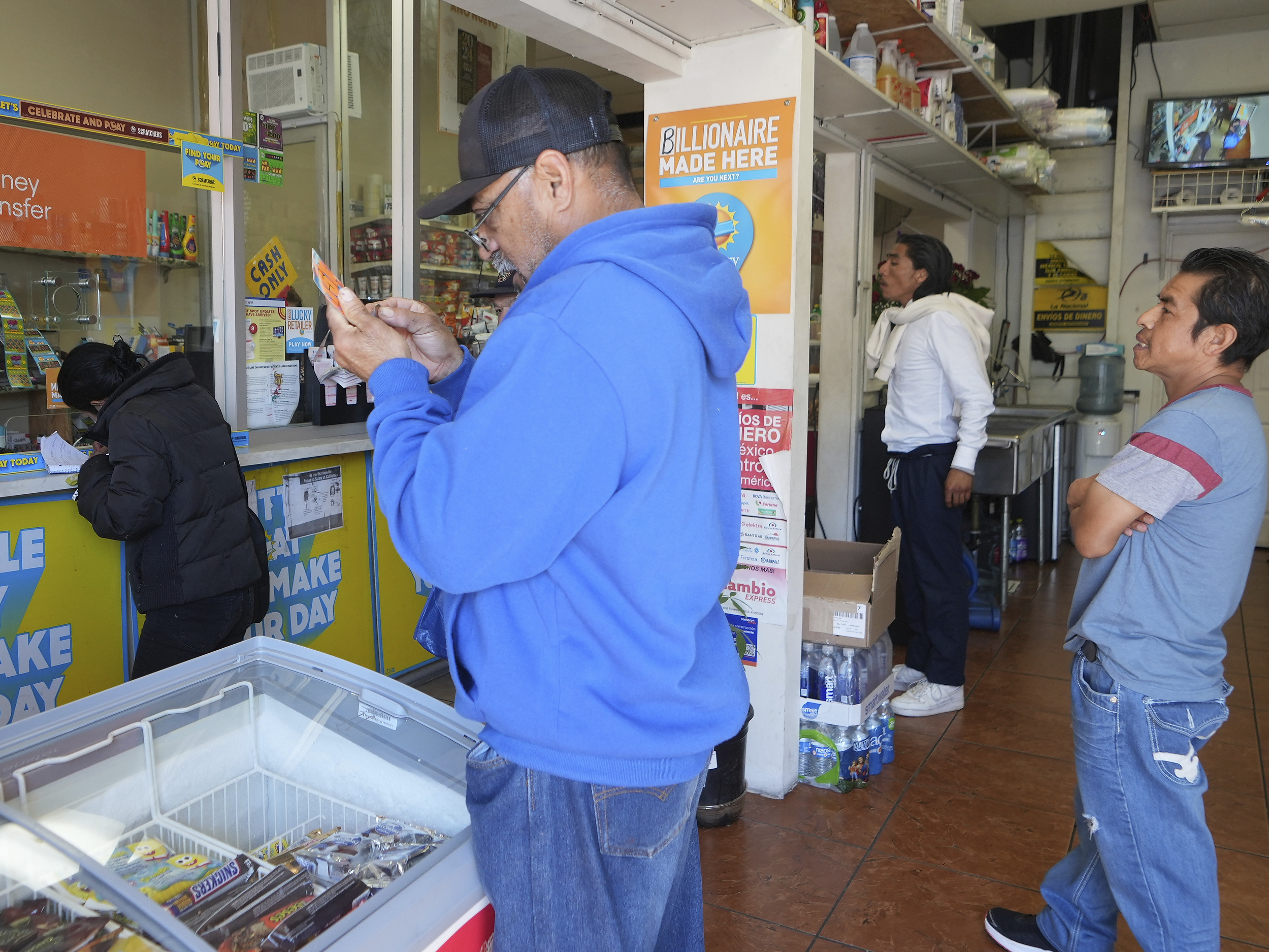 caption: Lottery players buy Powerball tickets at the Las Palmitas Mini Market in in the Fashion District downtown Los Angeles on Monday, April 1, 2024.
