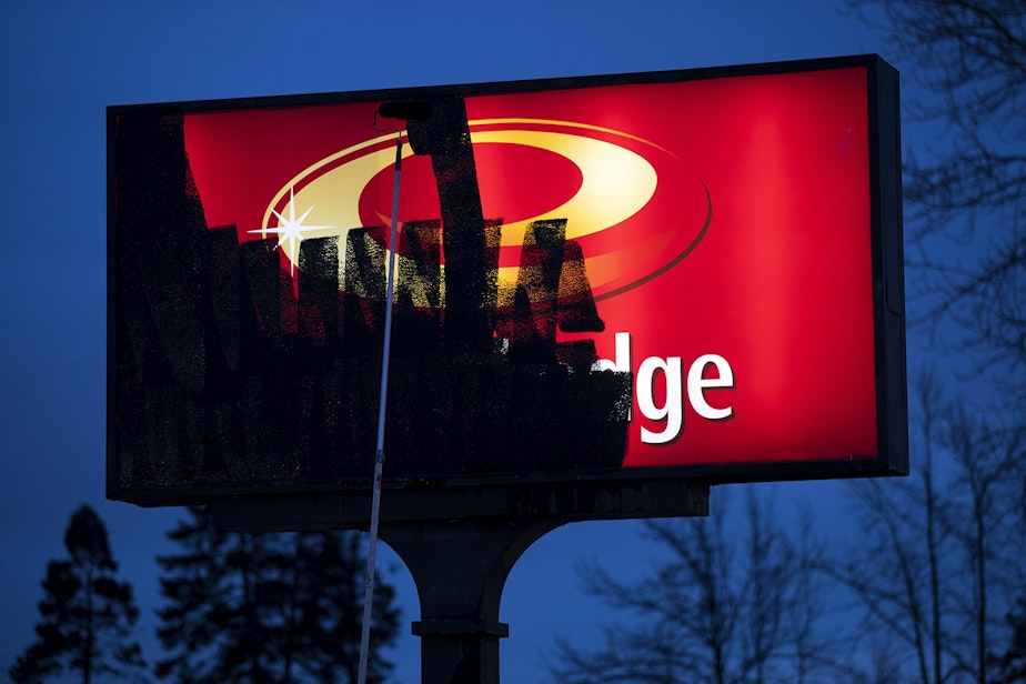 caption: A King County worker paints over an Econo Lodge sign on Friday, March 6, 2020, on Central Avenue North in Kent. 