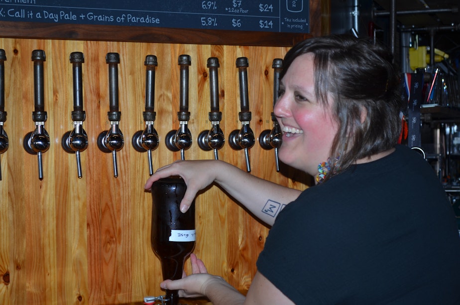 caption: Sara McCabe serves a customer at Flying Lion Brewing on reopening day, June 30.