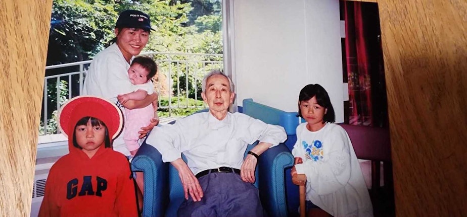 caption: Shosuke Sasaki (middle) poses for a family photo. The author is held by her mother, Akiko Newcomb. The author's cousins gather around "Uncle Shosuke."