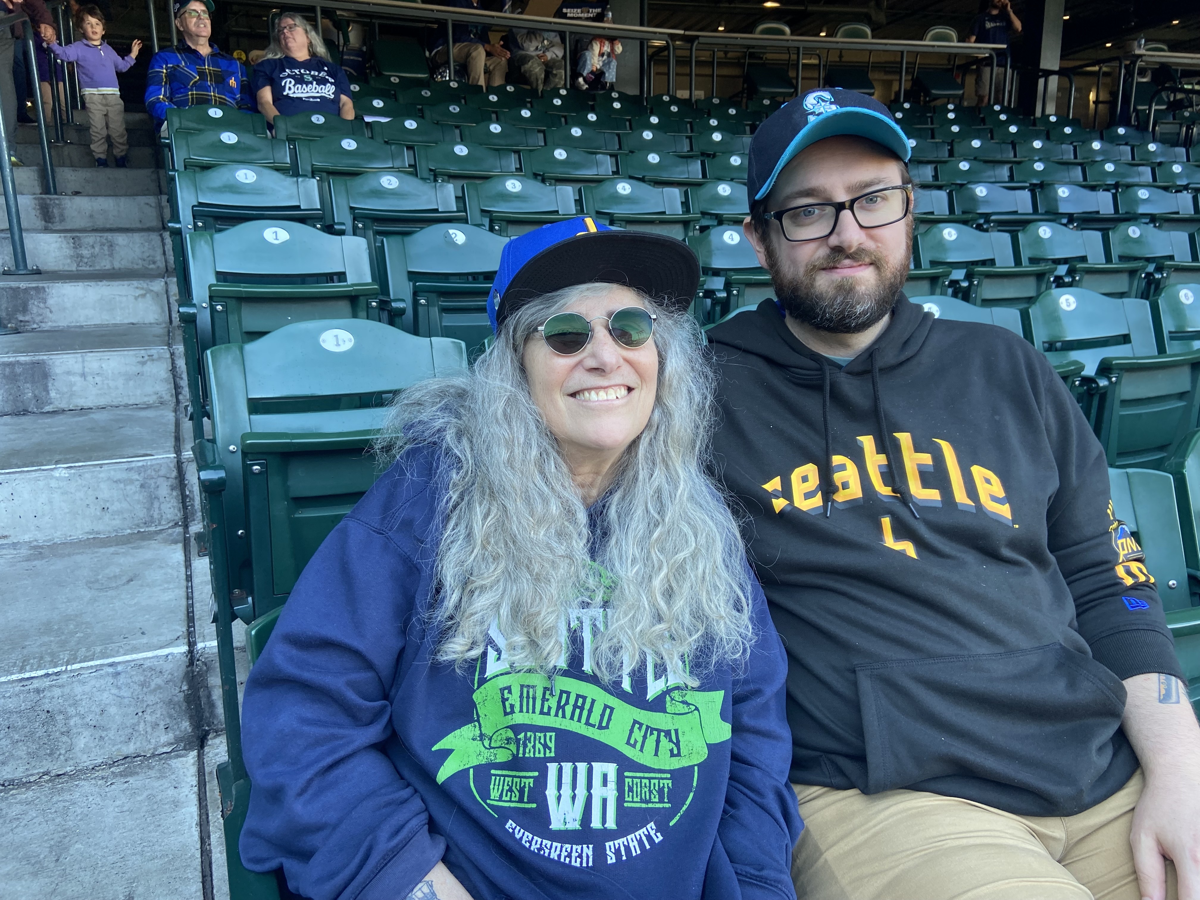 caption: Wendy Luvahn (left) left her job at Starbucks' headquarters early to catch the Game 3 watch party at T-Mobile Park. Her son, Sam Luvahn (right), joined her.