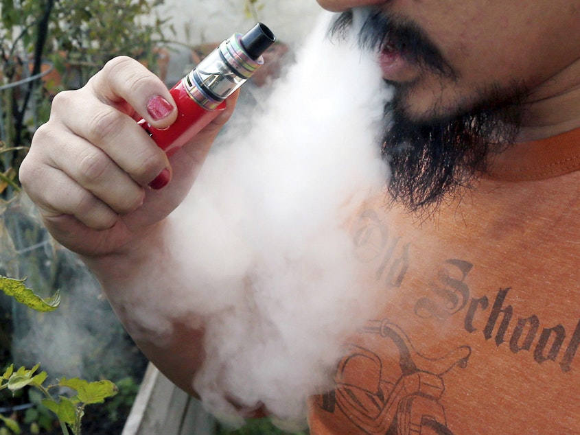caption: A man vapes with an electronic cigarette. On Thursday, the CDC said lung-injury patients reported using 152 different THC-containing product brands.