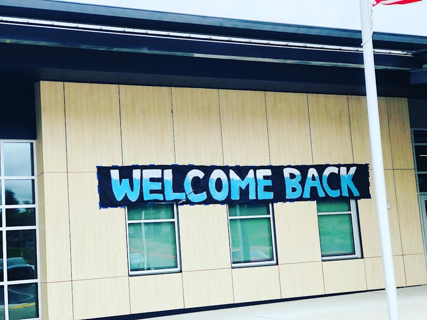 caption: A sign welcomes students back to Glacier Middle School in SeaTac in April 2021, after months of remote learning during the Covid-19 pandemic. 