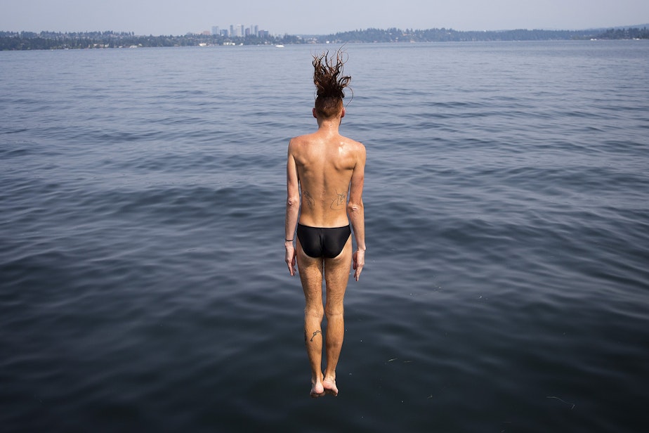 caption: Axel Kuehn, 29, jumps off of a dock into Lake Washington near Madrona Park on Monday, July 30, 2018, in Seattle.