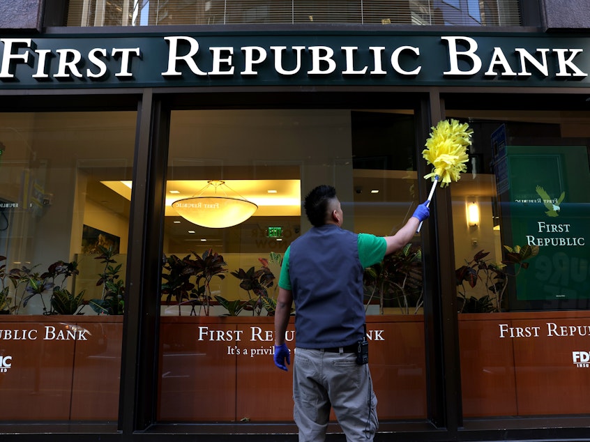 caption: A worker cleans the outside of a First Republic bank in San Francisco.