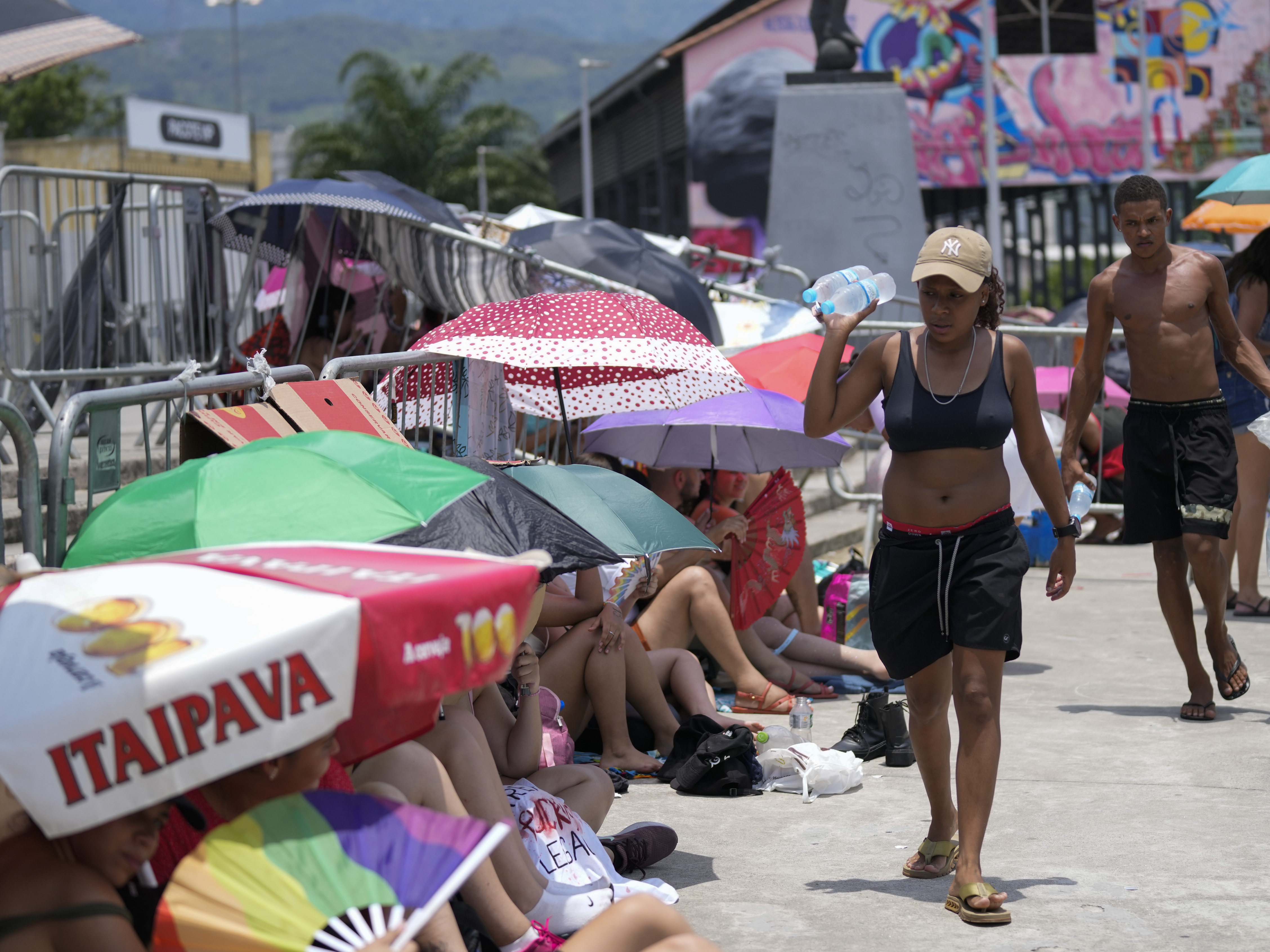 caption: Street vendors sell bottled water to Taylor Swift fans amid a heat wave before her Eras Tour concert outside the Nilton Santos Olympic stadium in Rio de Janeiro, Brazil, Saturday, Nov. 18, 2023.