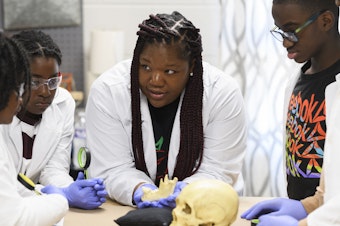 caption: Using a plastic skull, archaeologist Alicia Odewale teaches a lesson about Tulsa's ongoing search for mass graves containing victims of the city's 1921 race massacre. She taught it at Black History Saturdays, a free private program designed for students to learn unvarnished lessons in African-American history that teachers say a new law targeting race education has made harder to honestly teach.