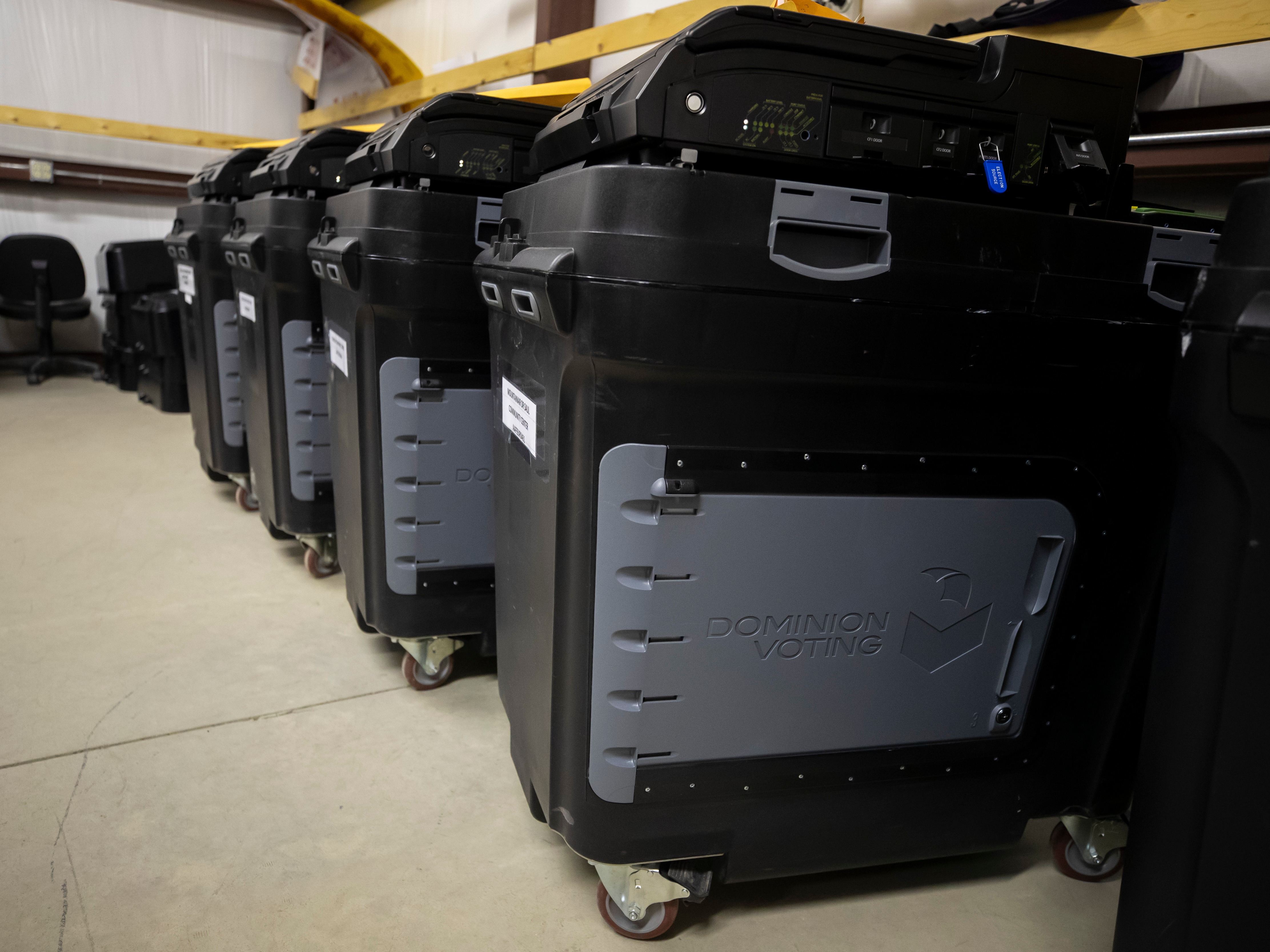 caption: Dominion Voting Systems ballot-counting machines are lined up at a Torrance County warehouse during a testing of election equipment in Estancia, N.M., on Sept. 29, 2022.