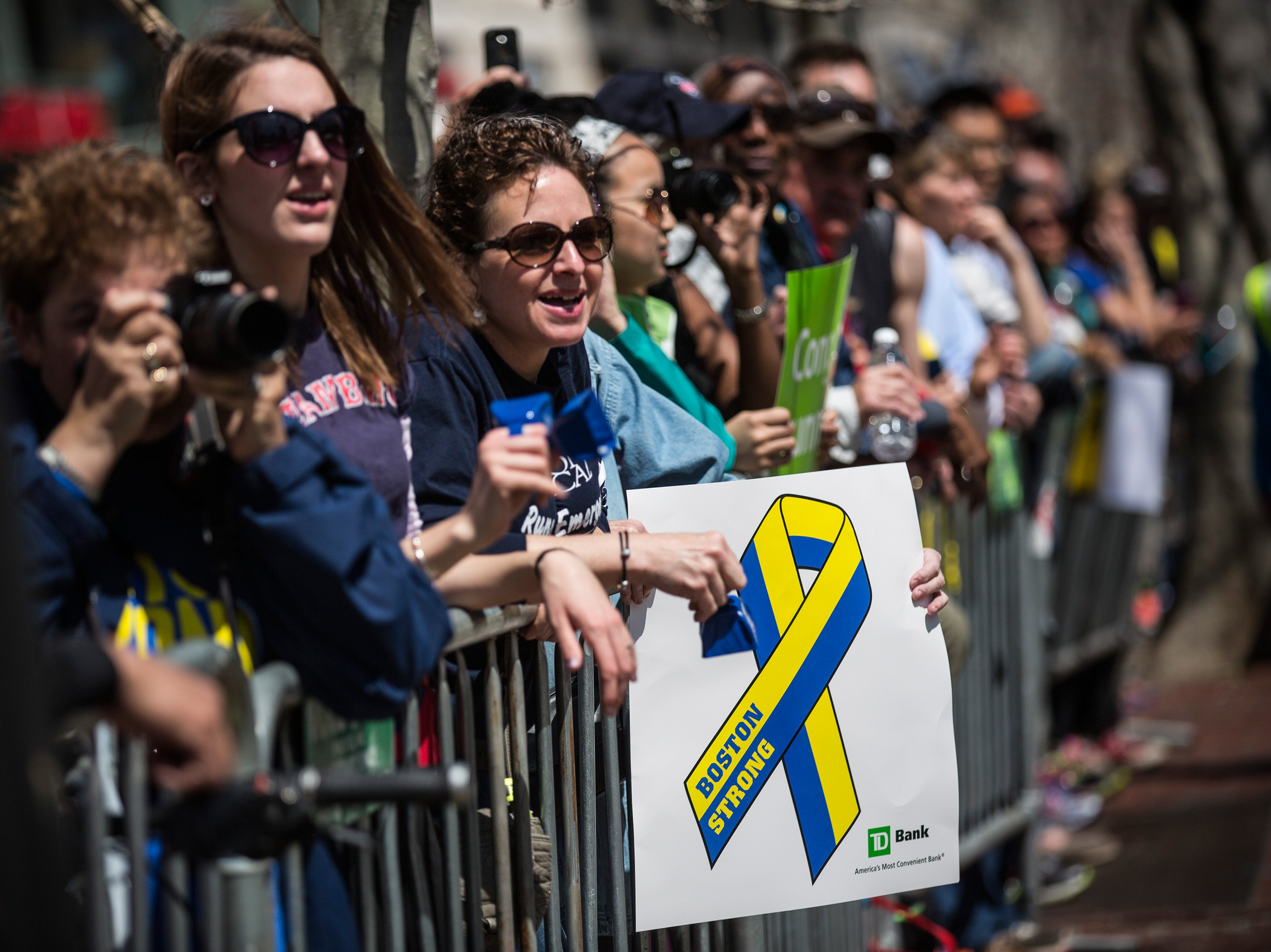 caption: Fans with a "Boston Strong" poster cheer on runners as they finish the Boston Marathon in April 2014.