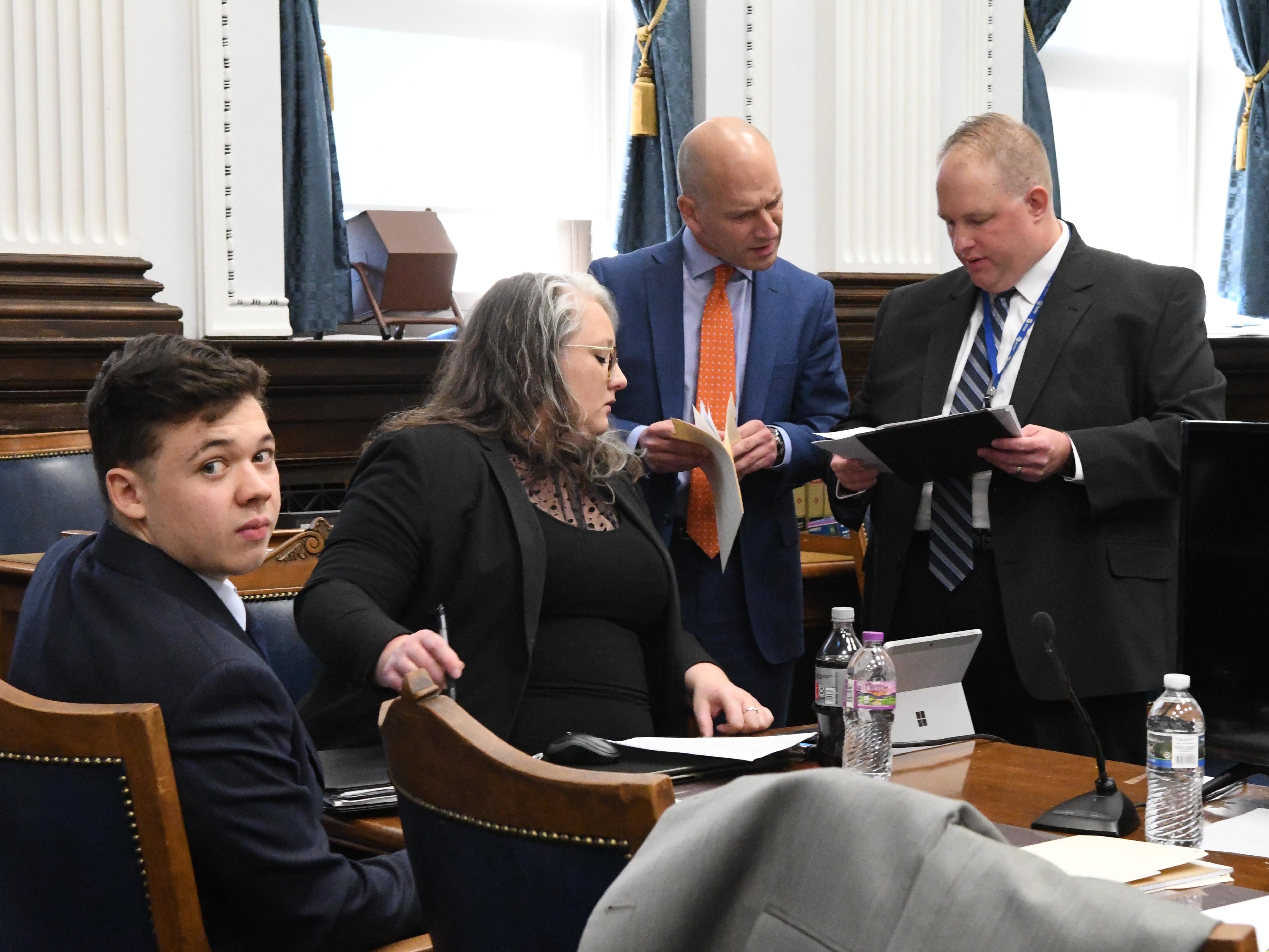 caption: Kyle Rittenhouse looks on as defense attorneys Natalie Wisco and Corey Chirafisi look at exhibits before court with Assistant District Attorney James Kraus right during the trial of Kyle Rittenhouse on November 5, 2021 in Kenosha, Wisconsin.