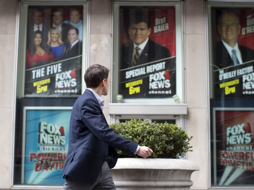 caption: A pedestrian walks past the News Corp. headquarters building in New York displaying posters featuring Fox News Channel personalities on April 19, 2017.