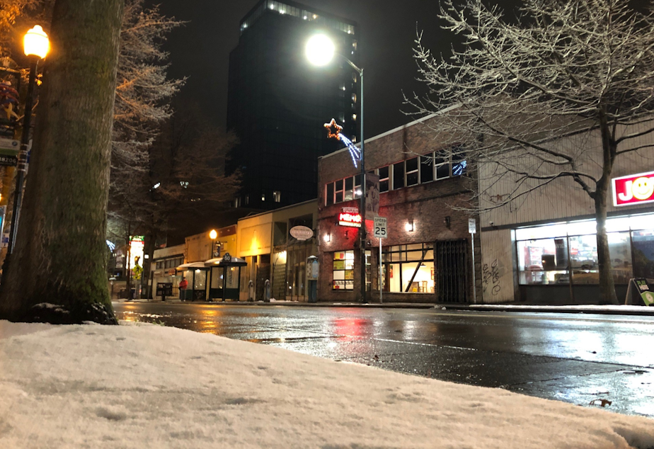 caption: Snow blankets the sidewalks of Seattle's University District, but doesn't stick long on University Avenue, Jan. 13, 2020. 