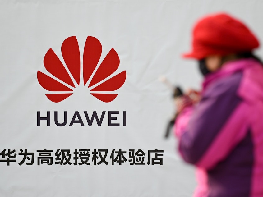 caption: A Justice Department indictment unsealed on Monday details an alleged conspiracy by the Chinese device maker Huawei to steal the details of a T-Mobile robot. Here, a woman uses her smartphone outside a Huawei store in Beijing on Tuesday.