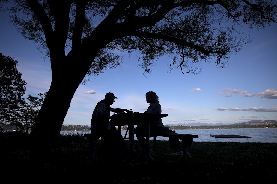 caption: Lee Markholt, left, and Tara Conklin, right, have a picnic on Friday, May 15, 2020, at Madrona Park in Seattle. 