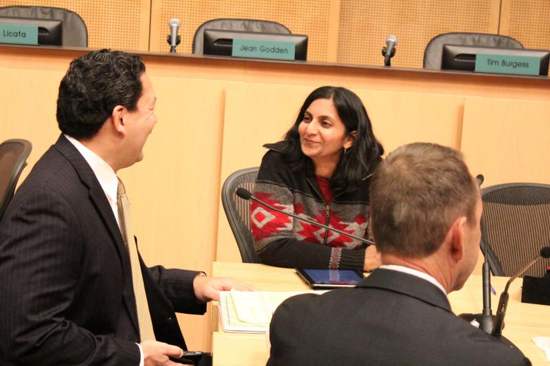 caption: Socialist City Councilmember Kshama Sawant jokes with City Councilmember Bruce Harrell at her first City Council meeting.