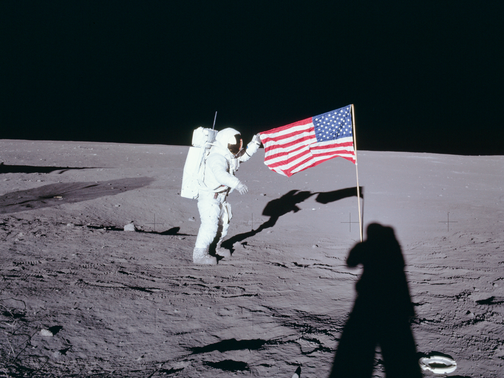 caption: From NASA: Apollo 12 commander Charles "Pete" Conrad unfurls the United States flag on the lunar surface during the first extravehicular activity on Nov. 19, 1969.