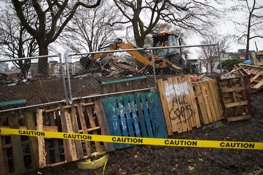 caption: The tents and belongings of unhoused community members are bulldozed and put into garbage trucks along with debris following the sweep of Cal Anderson Park on Friday, December 18, 2020, in Seattle. 